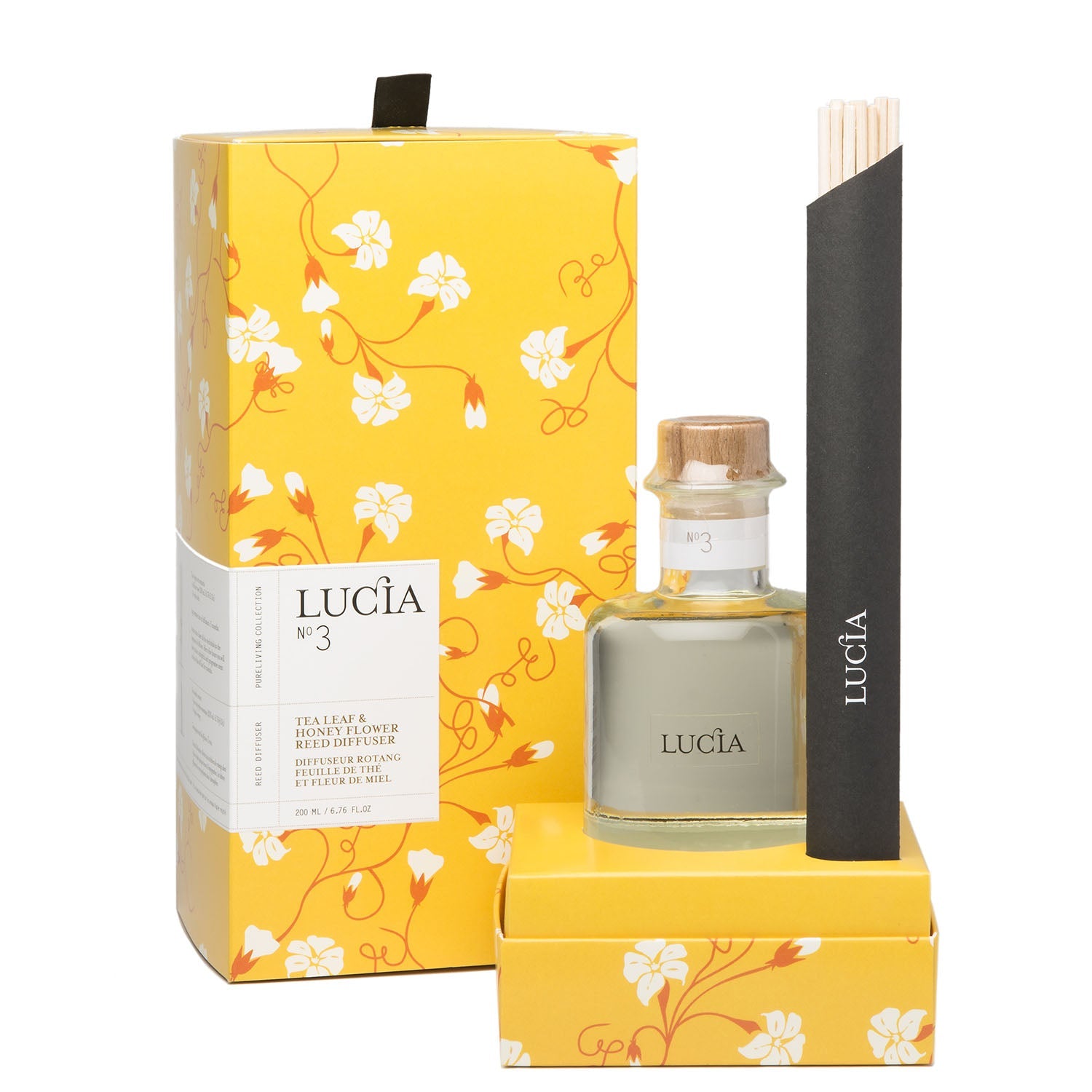 Diffuseur à bâtons bouteille claire et boîte en carton aux motifs floraux orangés.